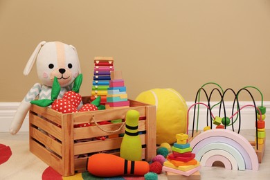 Set of different cute toys on floor near beige wall