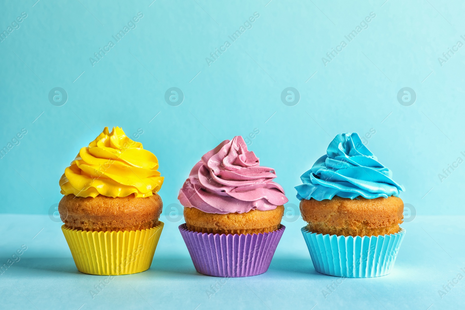 Photo of Delicious birthday cupcakes with cream on color background