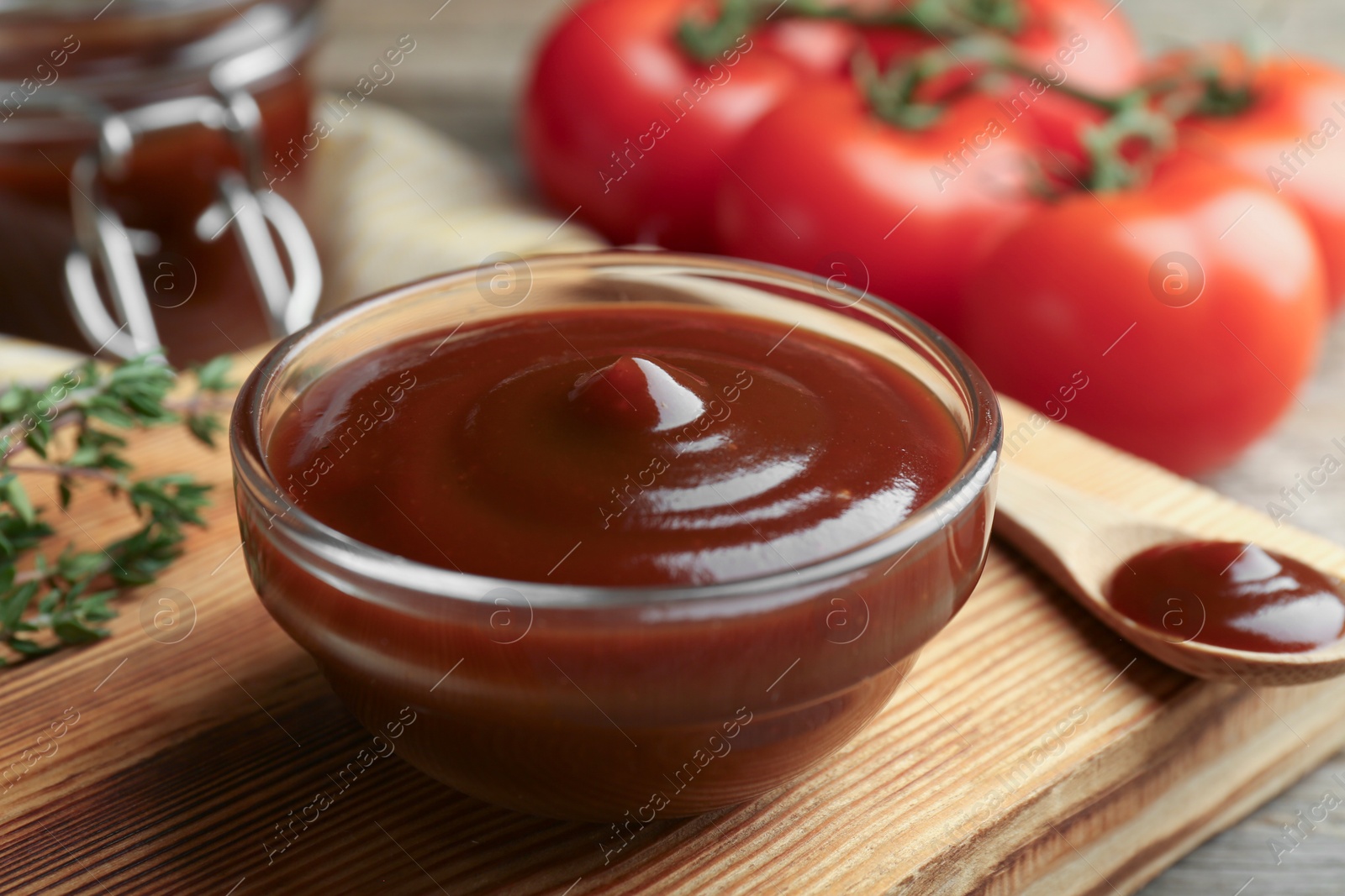 Photo of Tasty barbeque sauce in bowl and spoon on table, closeup