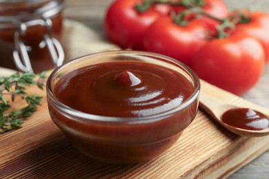 Photo of Tasty barbeque sauce in bowl and spoon on table, closeup