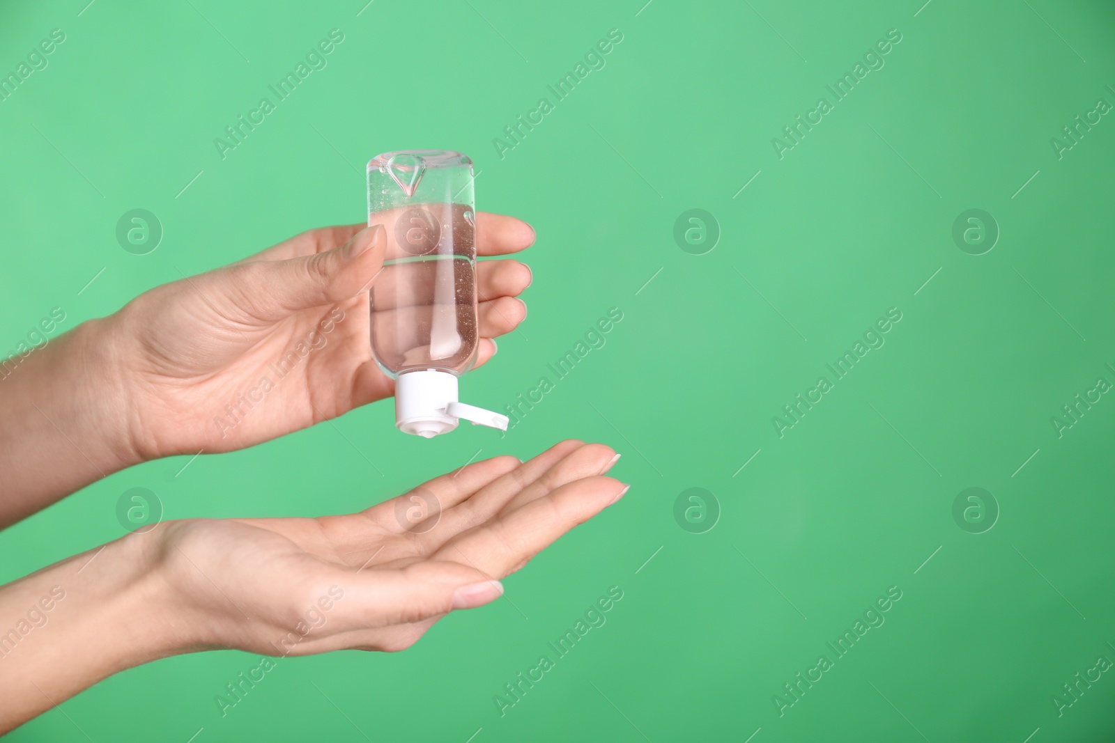 Photo of Woman applying antiseptic gel on green background, closeup. Space for text