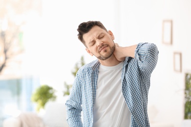 Photo of Young man suffering from neck pain  at home