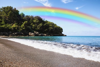 Image of Beautiful rainbow in blue sky over beach and sea on sunny day