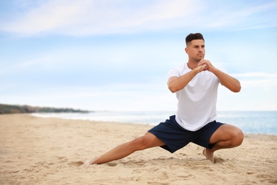 Muscular man doing exercise on beach, space for text. Body training