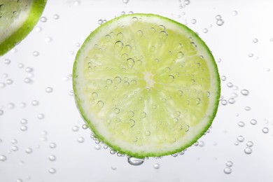 Photo of Juicy lime slice in soda water, closeup