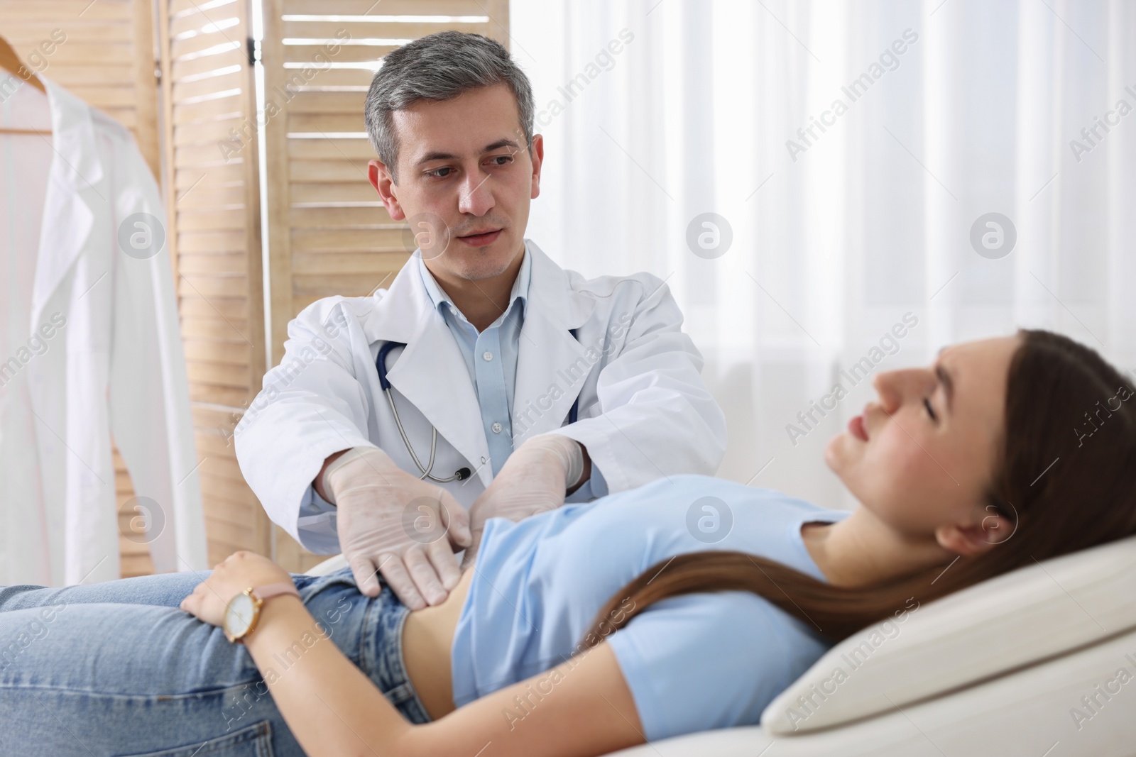 Photo of Gastroenterologist examining patient with stomach pain in clinic