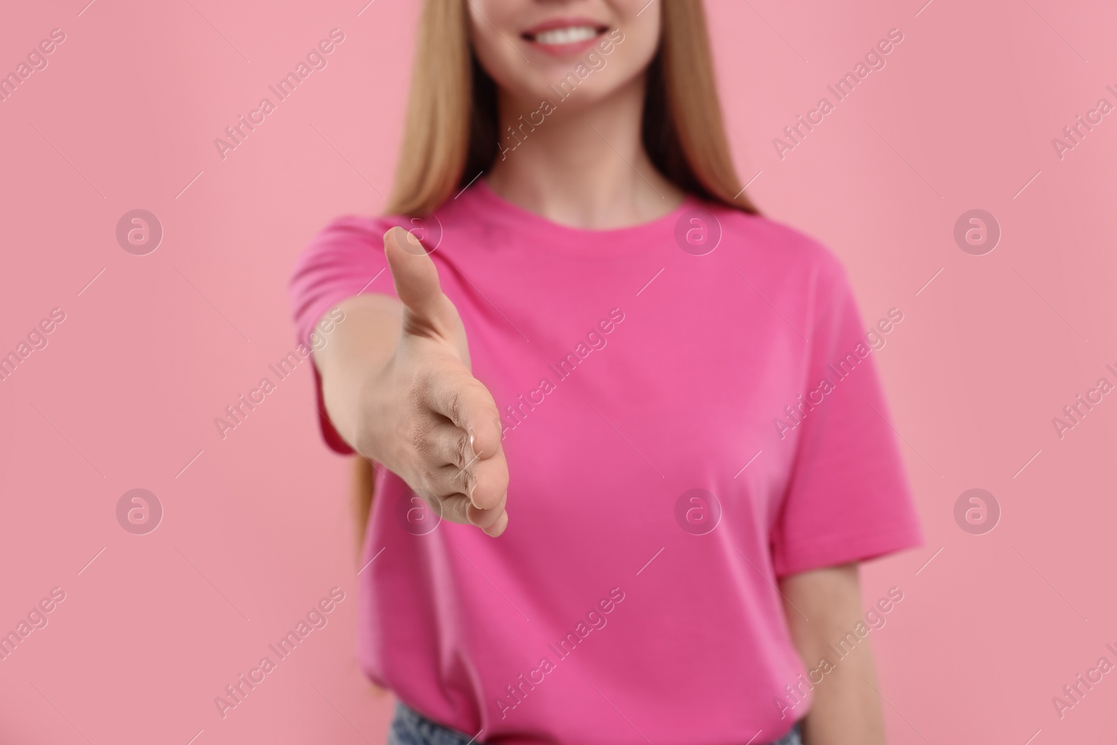 Photo of Woman welcoming and offering handshake on pink background, closeup