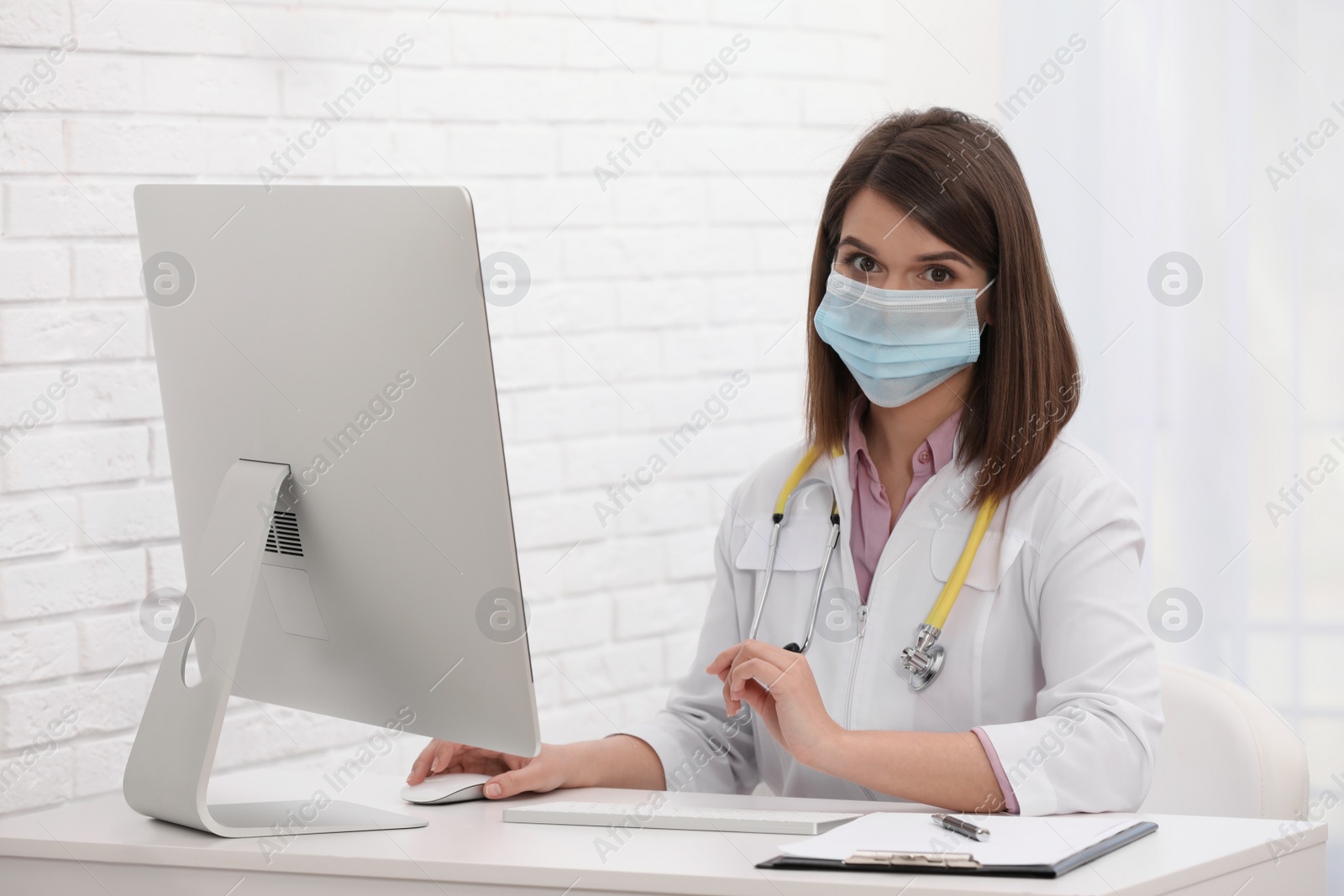 Photo of Portrait of pediatrician with protective mask at table in clinic