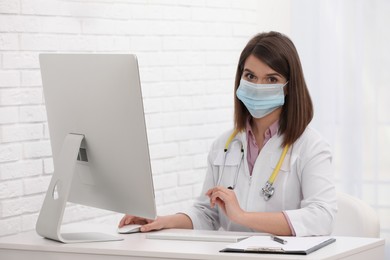 Portrait of pediatrician with protective mask at table in clinic