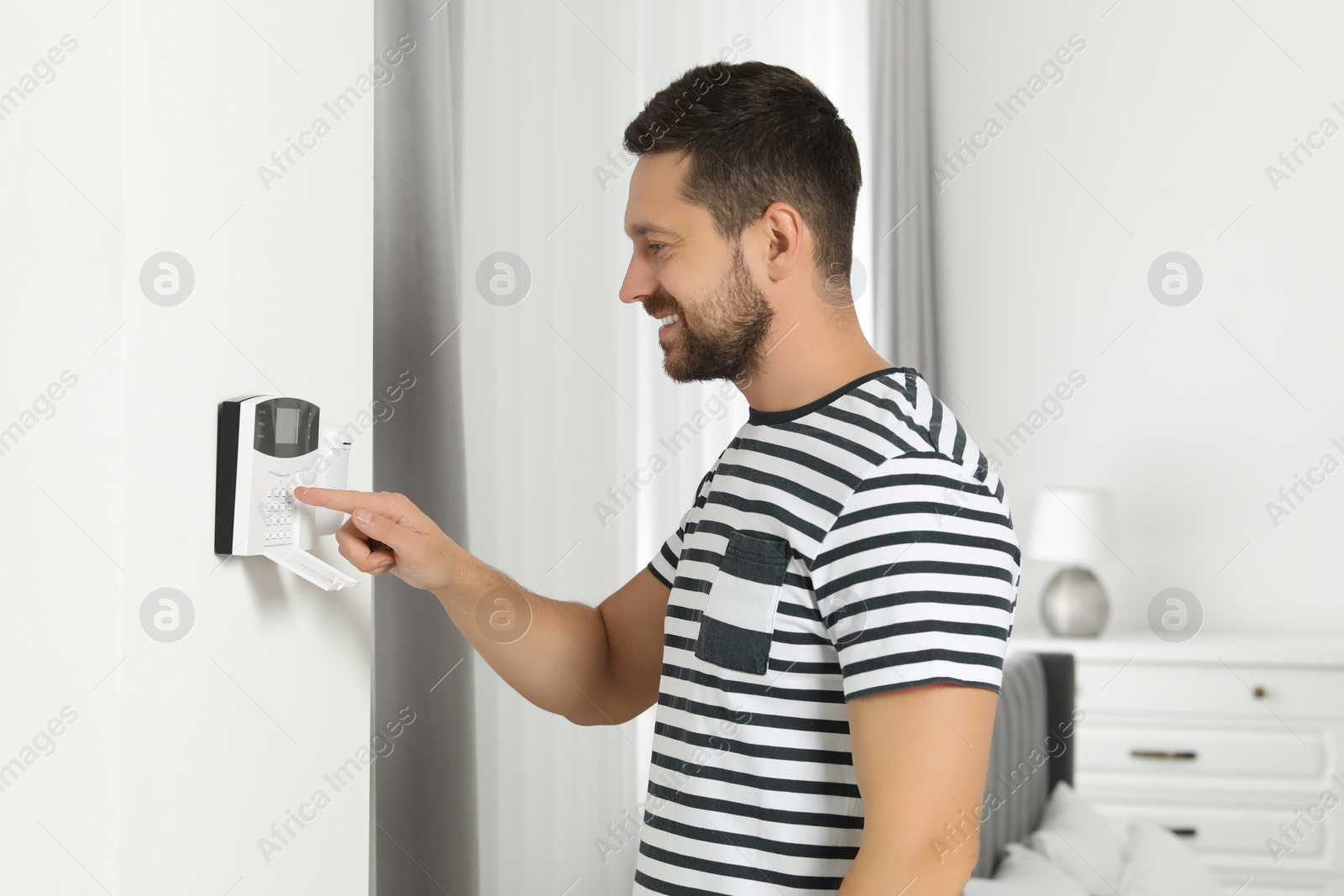 Photo of Man entering code on home security system indoors