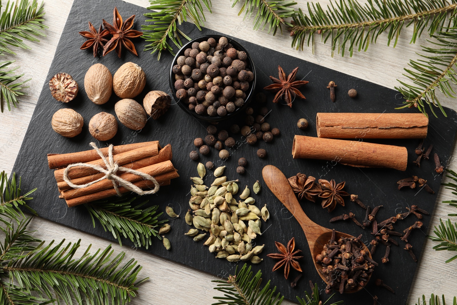 Photo of Different spices and fir branches on wooden table, flat lay