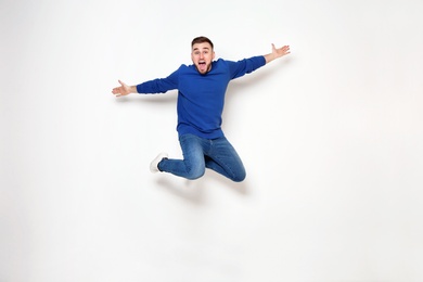 Full length portrait of handsome man jumping on white background