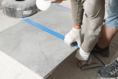 Photo of Worker measuring tiles for installation, closeup view