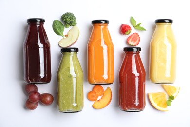 Flat lay composition with bottles of colorful juices and fresh ingredients on white background