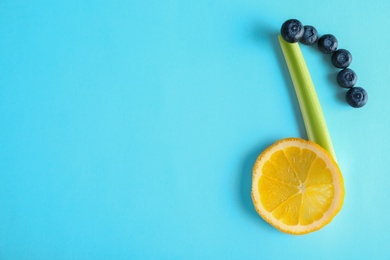 Photo of Musical note made of celery, lemon and berries on color background, top view. Space for text