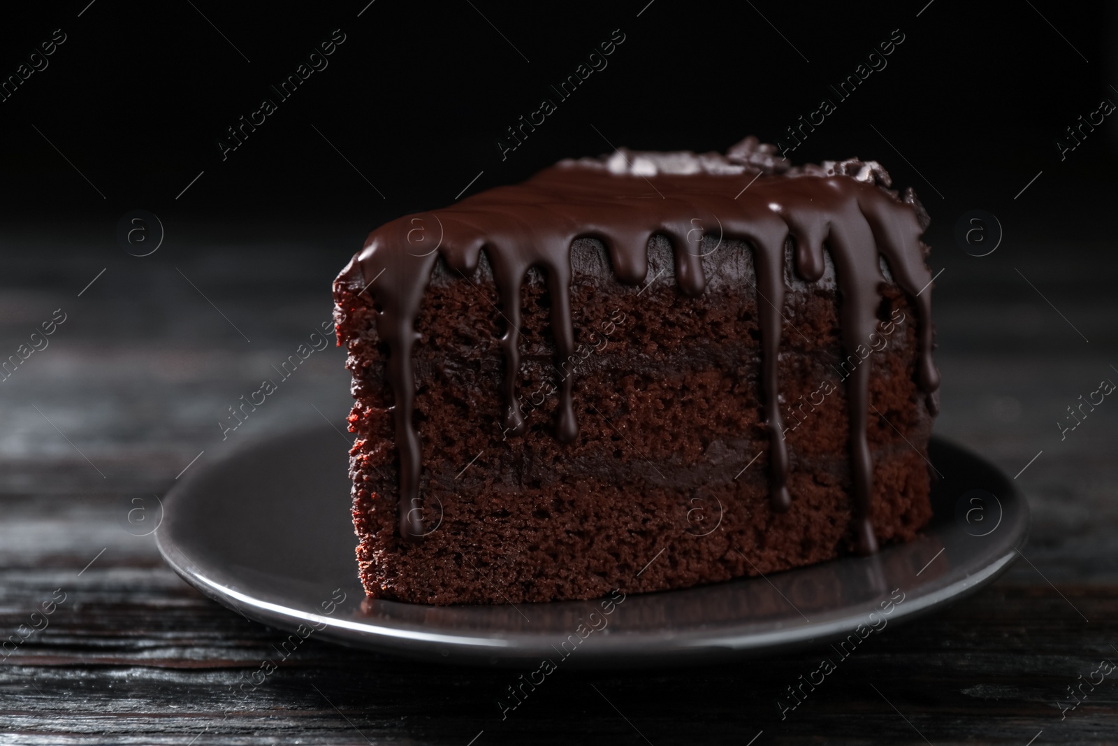 Photo of Delicious chocolate cake on black wooden table, closeup