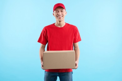 Happy courier with parcel on light blue background