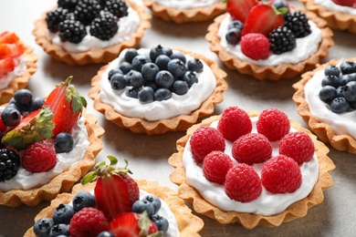 Photo of Many different berry tarts on table. Delicious pastries