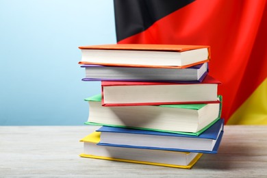 Photo of Learning foreign language. Different books on wooden table near flag of Germany