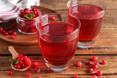 Photo of Tasty cranberry juice in glasses and fresh berries on wooden table, closeup