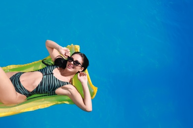 Photo of Beautiful young woman with inflatable mattress in swimming pool on sunny day. Space for text