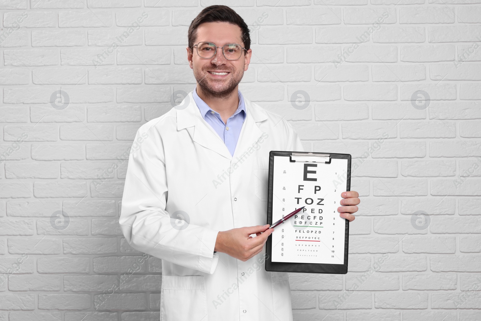 Photo of Ophthalmologist pointing at vision test chart near white brick wall