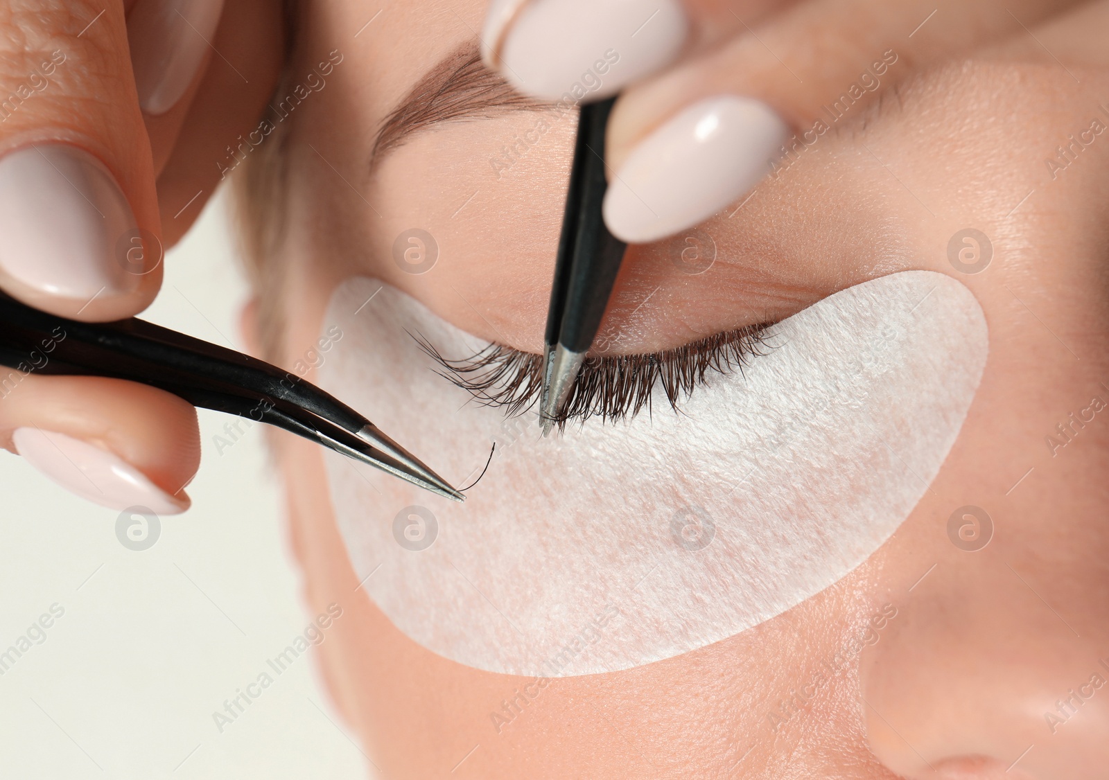 Photo of Young woman undergoing eyelash extension procedure, closeup