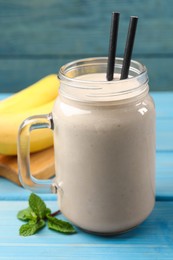 Mason jar with banana smoothie on light blue wooden table