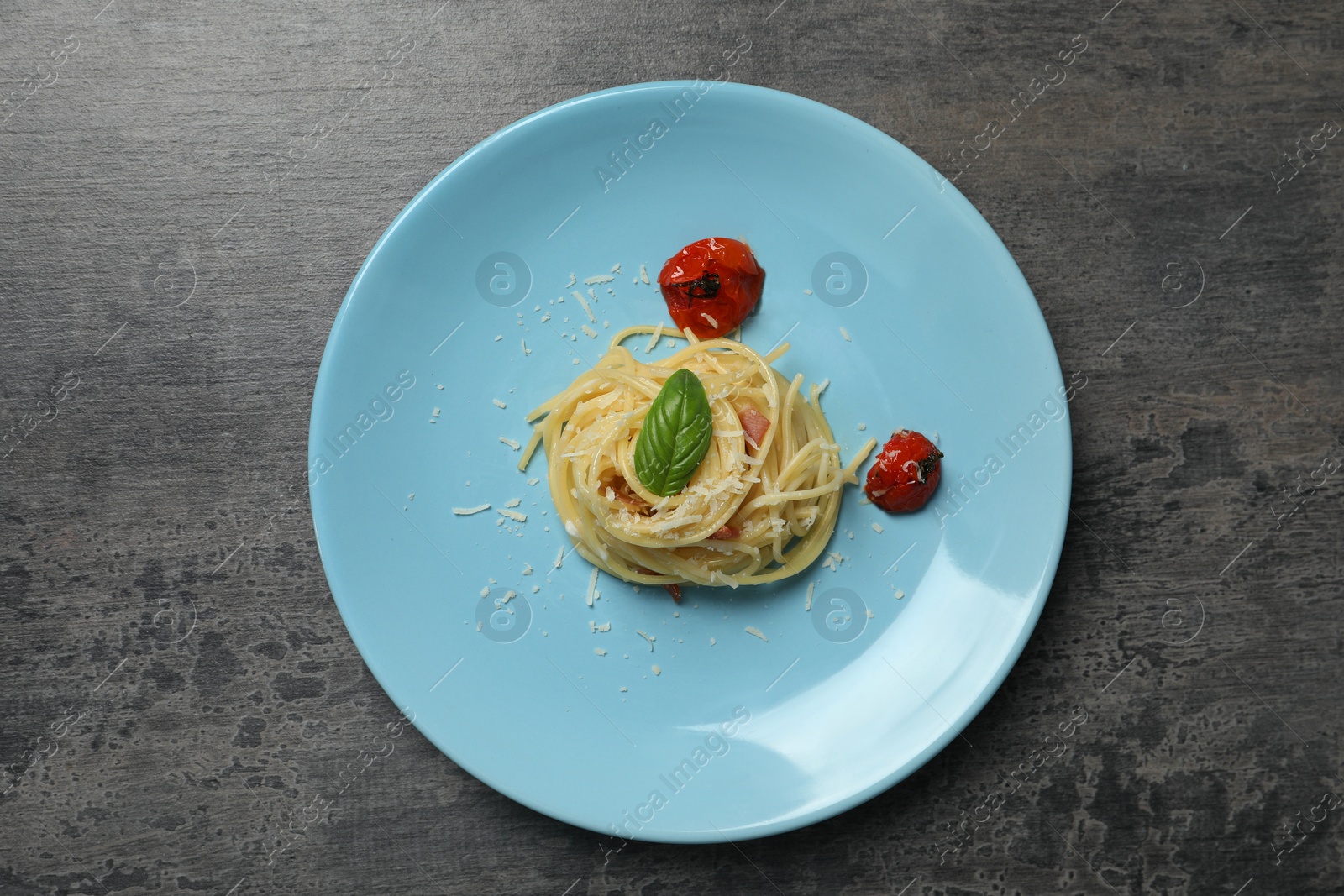 Photo of Tasty spaghetti with tomatoes and cheese on grey table, top view. Exquisite presentation of pasta dish