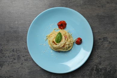 Tasty spaghetti with tomatoes and cheese on grey table, top view. Exquisite presentation of pasta dish