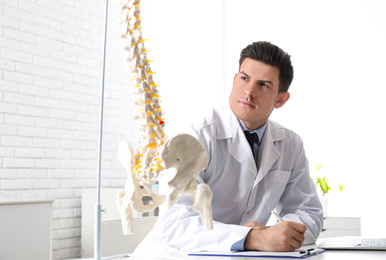 Photo of Professional orthopedist at table in medical office