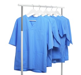 Light blue medical uniforms on rack against white background