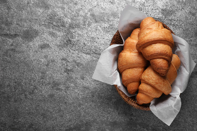 Tasty fresh croissants on grey table, top view. Space for text