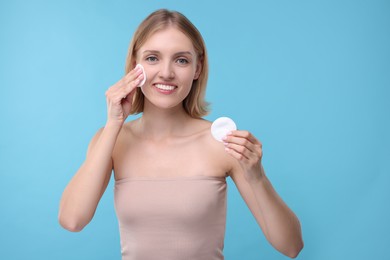 Photo of Young woman with cotton pads on light blue background