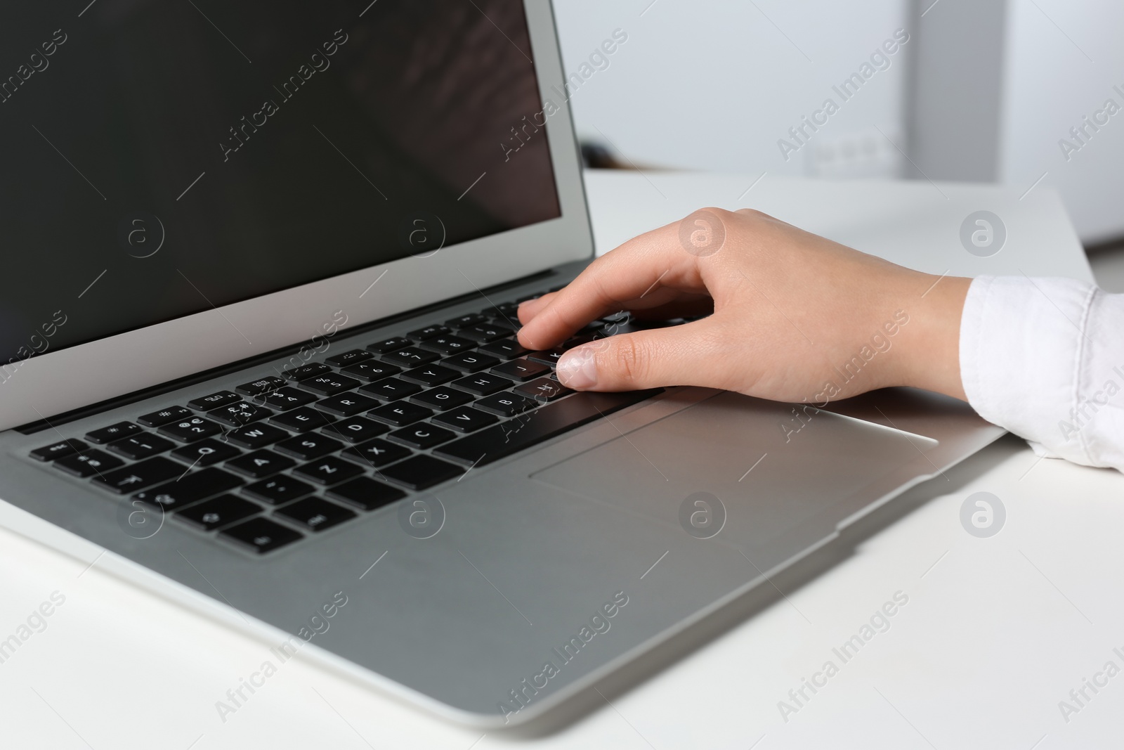 Photo of Woman working on laptop at white table in office, closeup