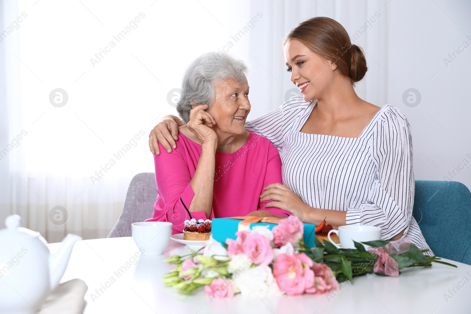 Photo of Young woman congratulating her senior mom at home. Happy Mother's Day