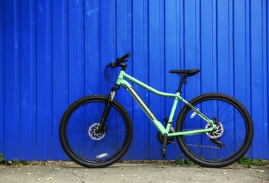 Modern bicycle near blue metal fence outdoors