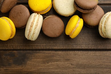 Photo of Delicious macarons on wooden table, flat lay. Space for text