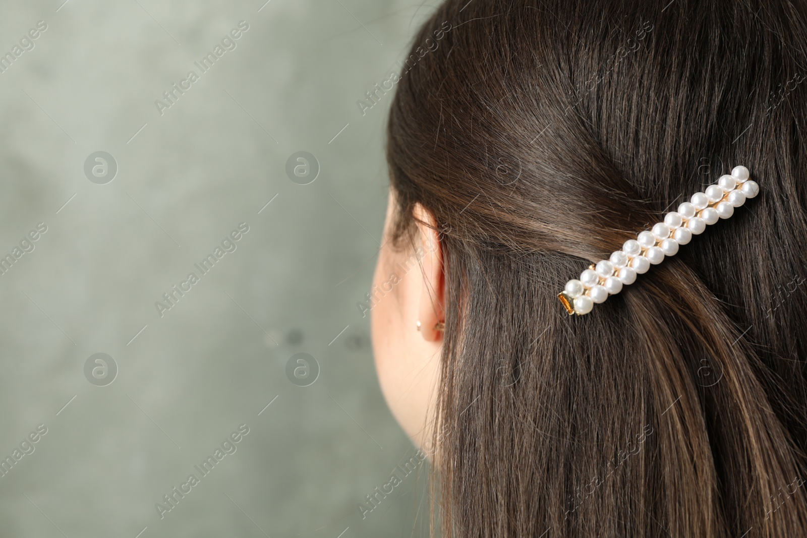 Photo of Young woman with beautiful hair clip on grey background, closeup. Space for text