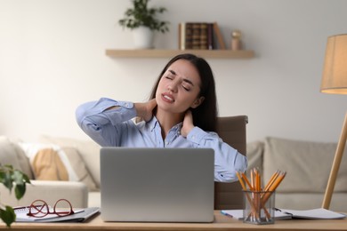 Photo of Young woman suffering from neck pain at table in office