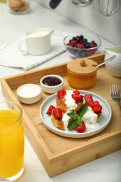 Photo of Delicious cottage cheese pancakes with fresh strawberries sour cream and mint served on white countertop