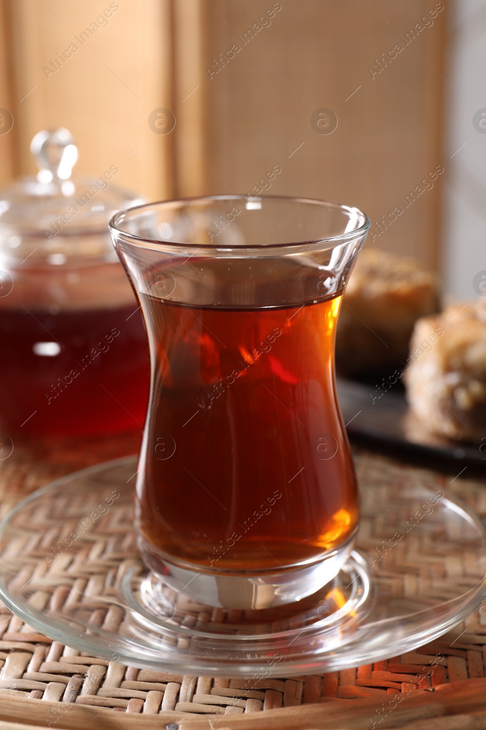 Photo of Traditional Turkish tea in glass on wicker table, closeup