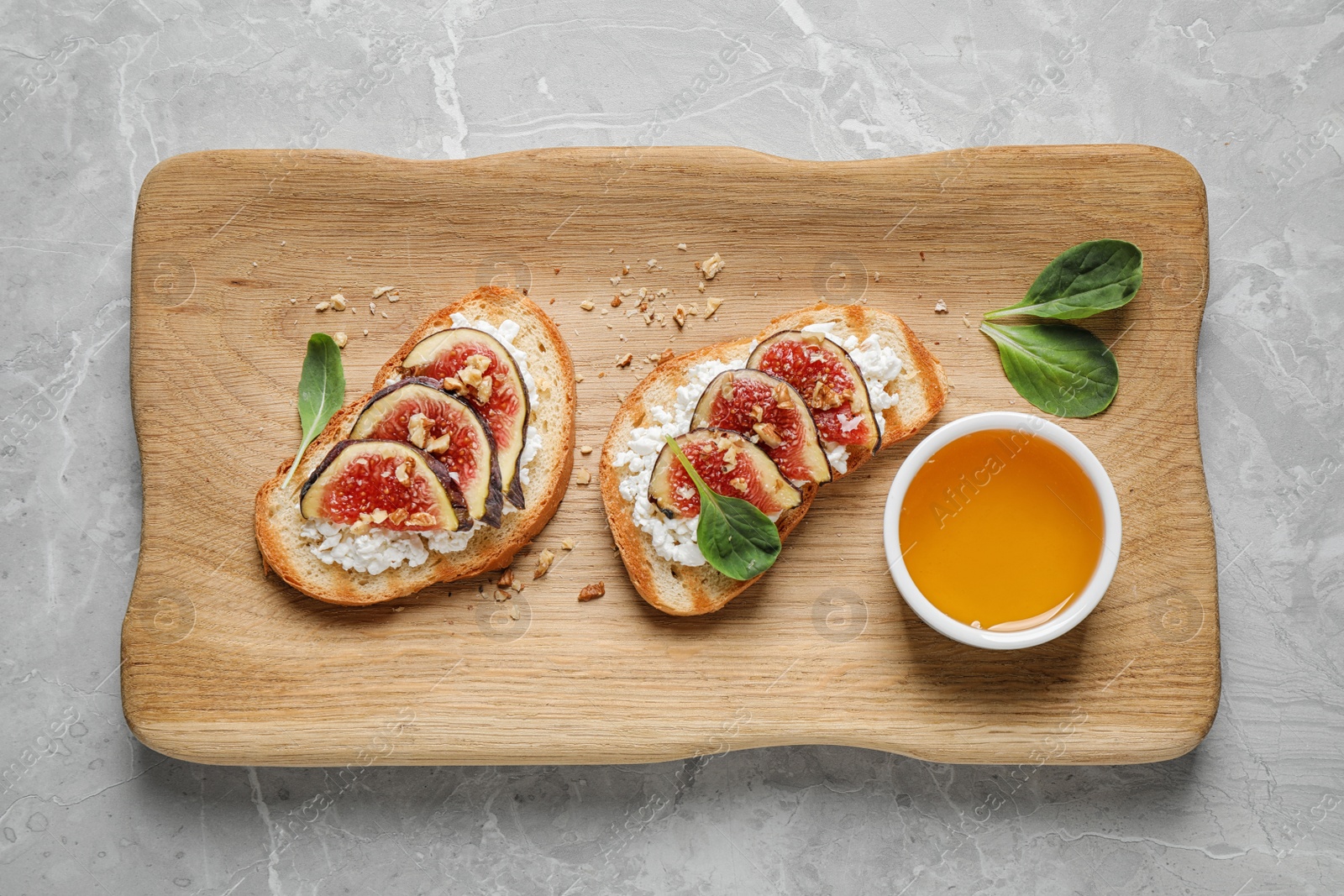 Photo of Bruschettas with cheese, figs and honey served on marble table, top view