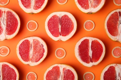 Photo of Flat lay composition with condoms and grapefruits on orange background. Erotic concept