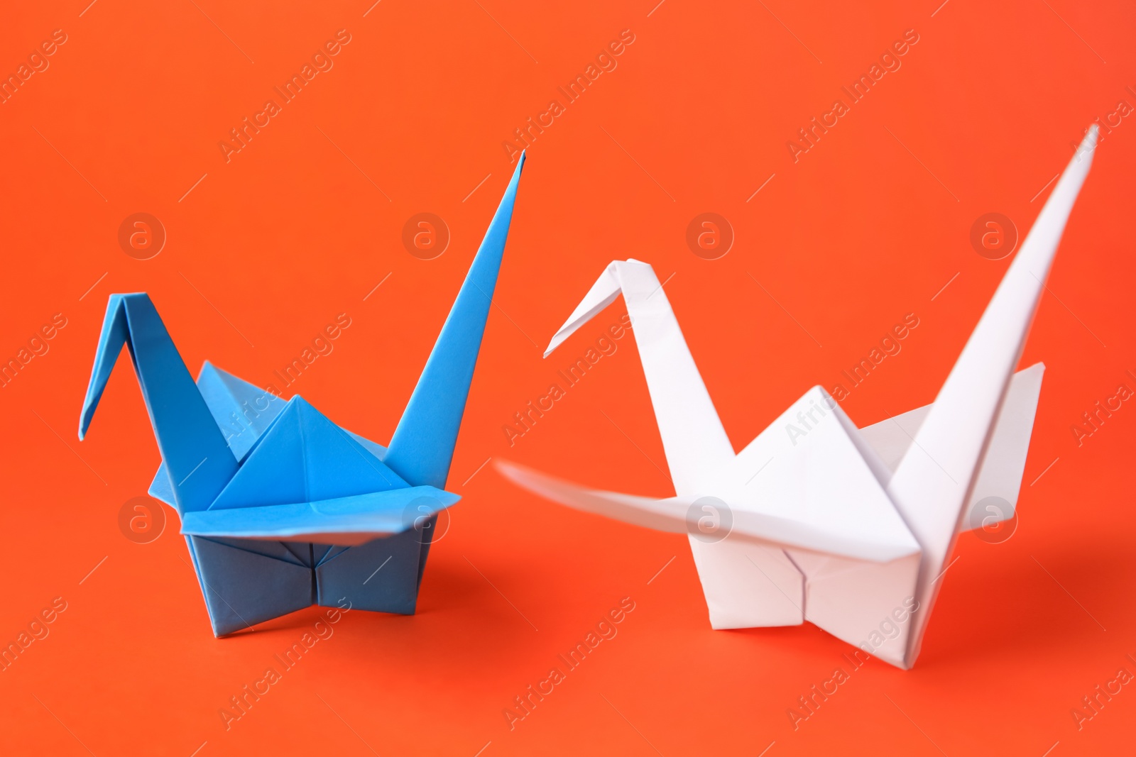 Photo of Colorful paper origami cranes on orange background, closeup