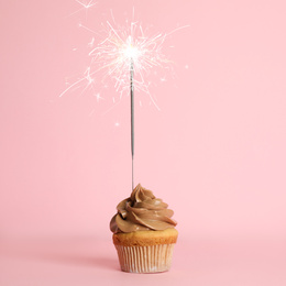 Birthday cupcake with sparkler on pink background