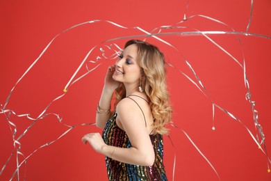 Happy woman and falling down serpentines on red background