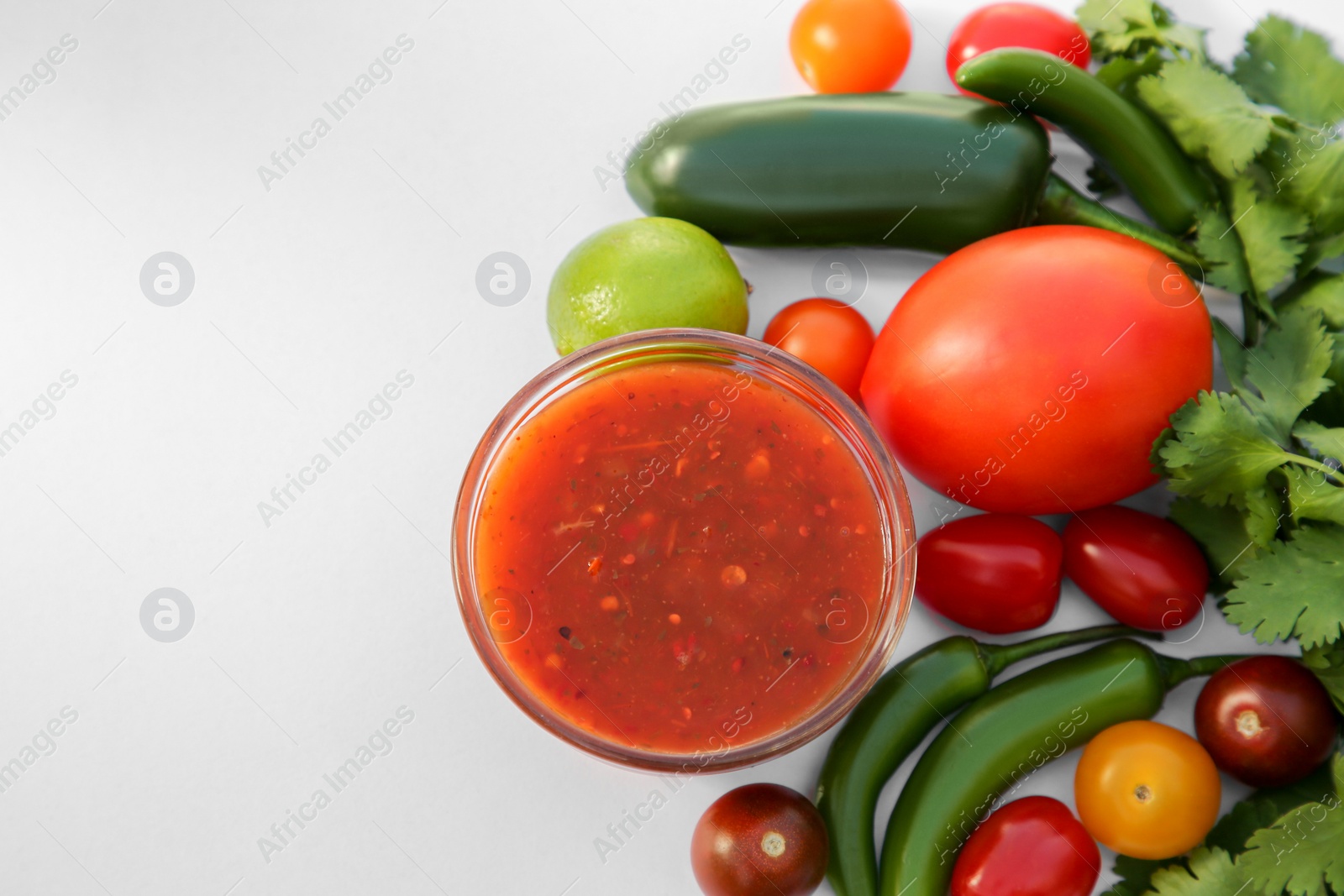 Photo of Bowl with delicious salsa sauce and ingredients on white background, flat lay. Space for text