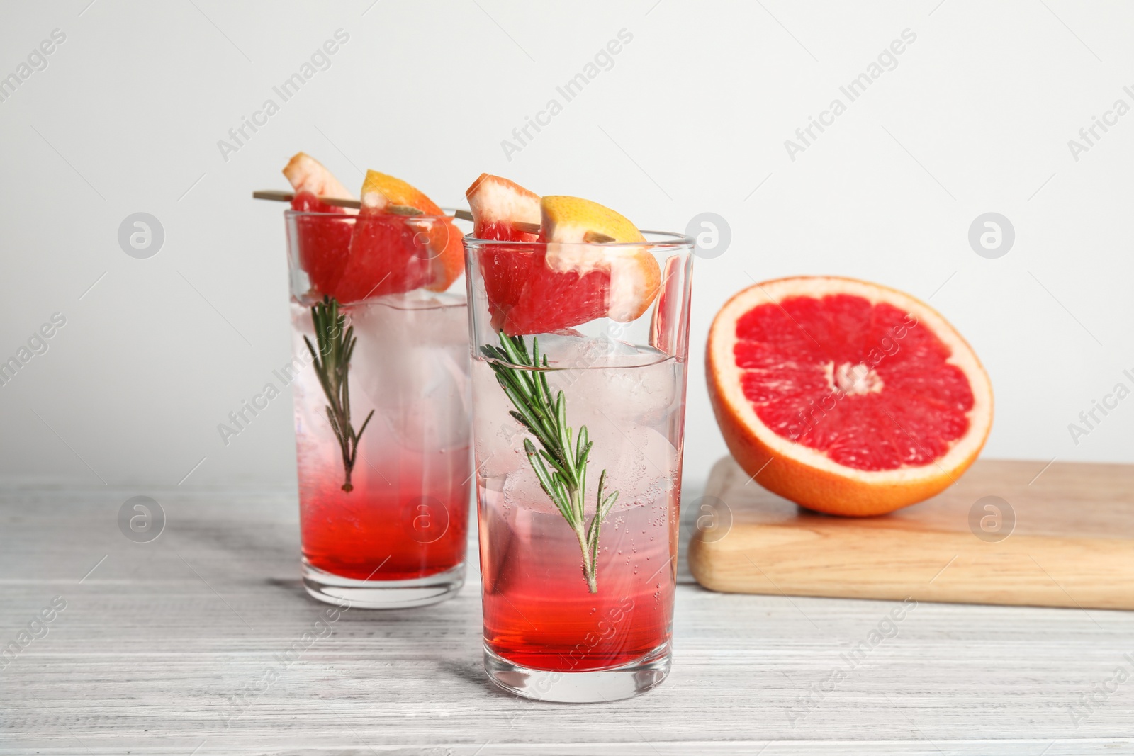 Photo of Glasses of cocktail and grapefruit half on table