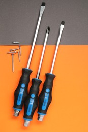 Photo of Set of screwdrivers and screws on color background, flat lay